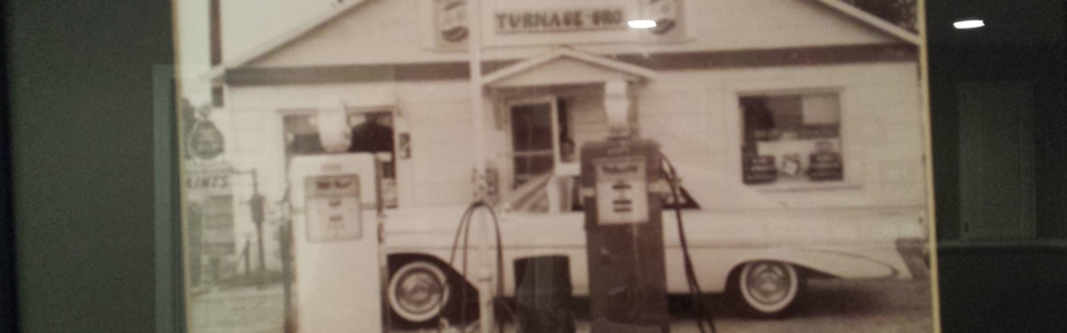 Vintage photo of small store with gas pump and classic car.