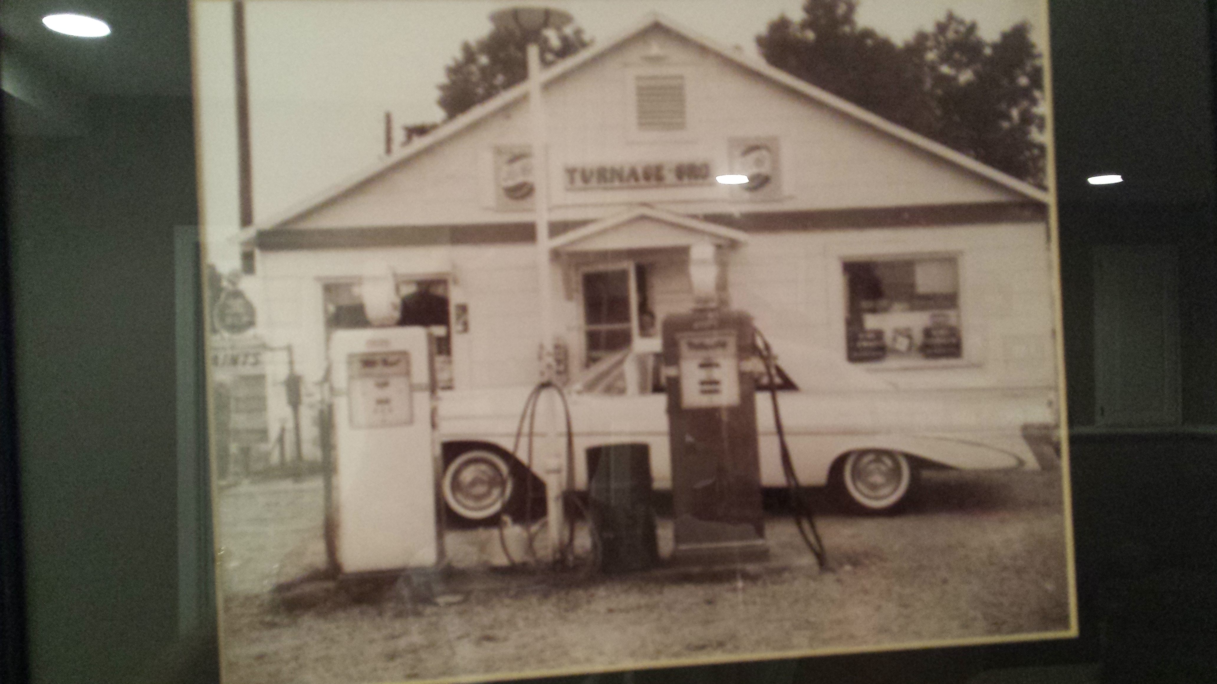 Vintage photo of small store with gas pump and classic car.